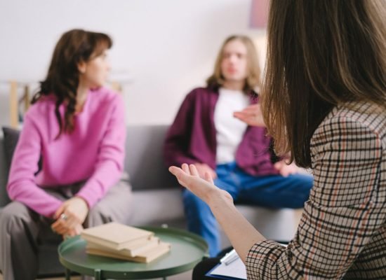Engaged counseling session with three adults discussing together in a cozy indoor setting.