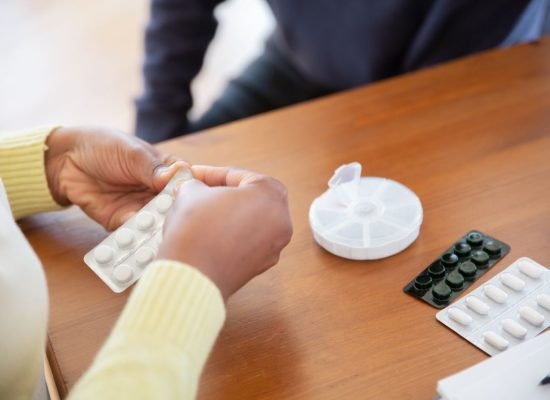 Close-up of a nurse organizing pills and medications on a table in a care setting.